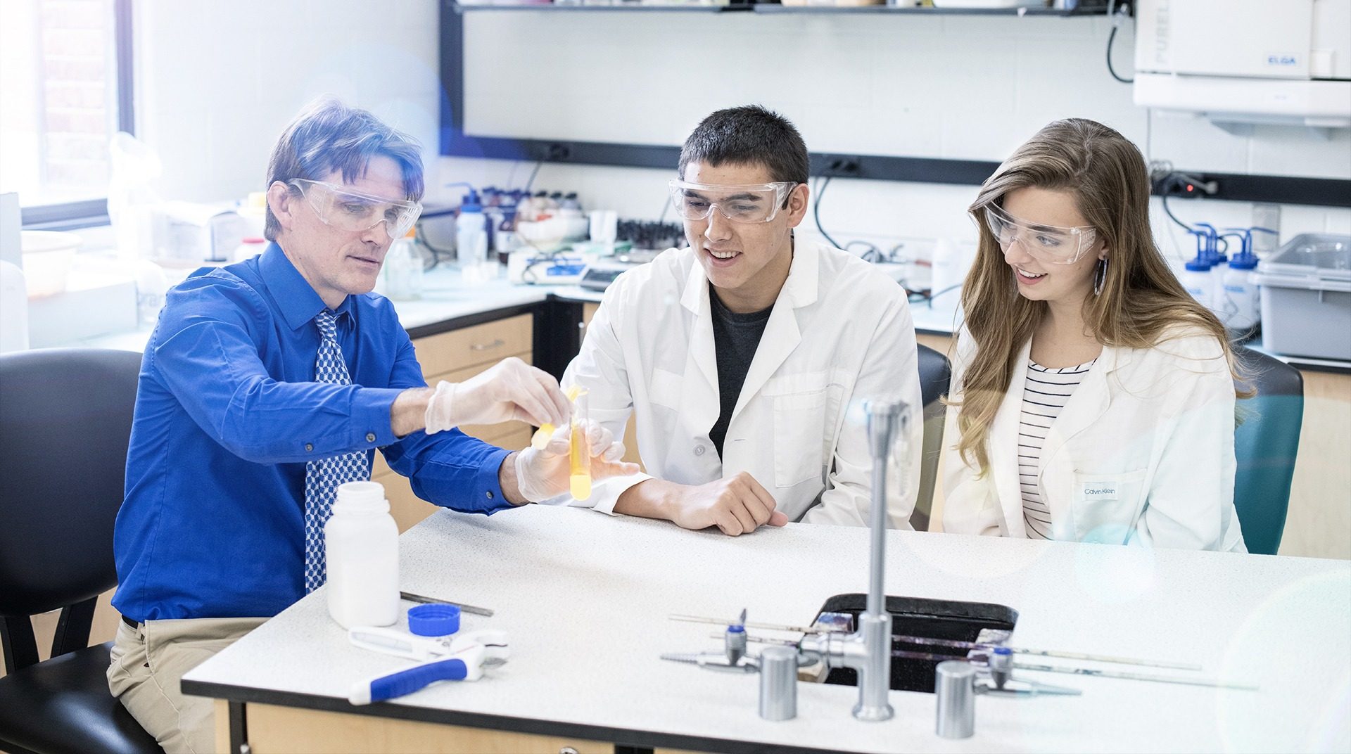 Professor mentoring science students in microbiology lab