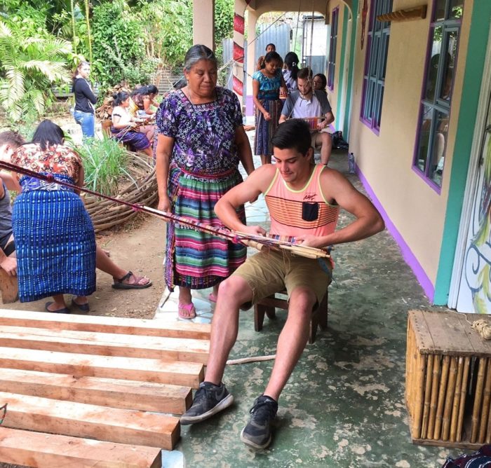 Student weaving on back strap loom in Guatemalan village