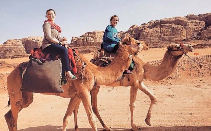 Two female Spring Arbor University students riding camels in the desert in Jordan