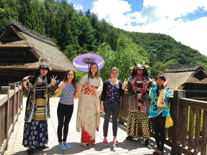 Spring Arbor students with hosts in traditional Japanese dress on sunny rural bridge