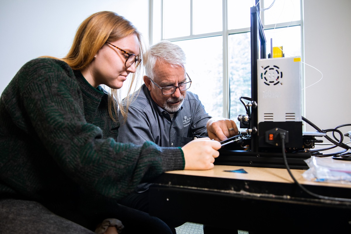 Student works on 3d printer with Dr. DeLap