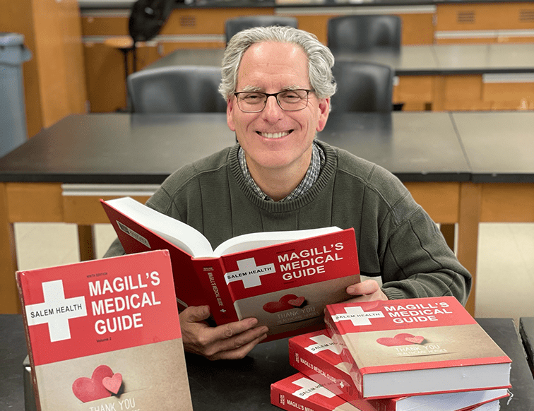 Professional Michael Buratovich, Ph.D. posed with the Magill Medical Guide, 9th edition.