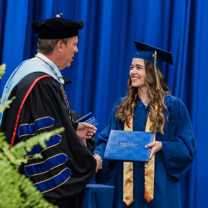 Jasmine Pattison shaking hands with President Ellis at the fall 2022 commencement.