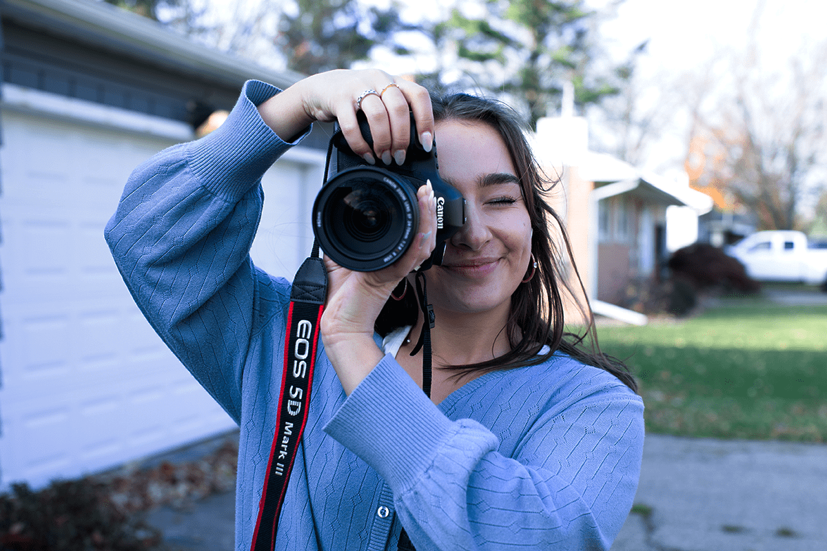 Student photographer Bella Chirco holding the camera up to her face