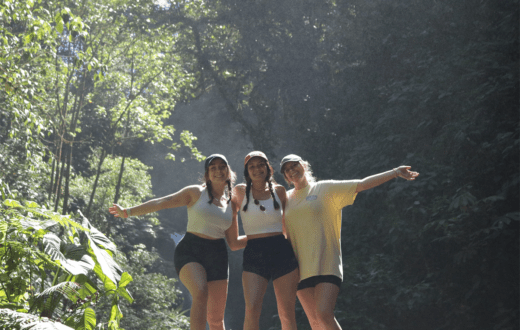 Three girls standing on a rock in front of a waterfall in Costa Rica