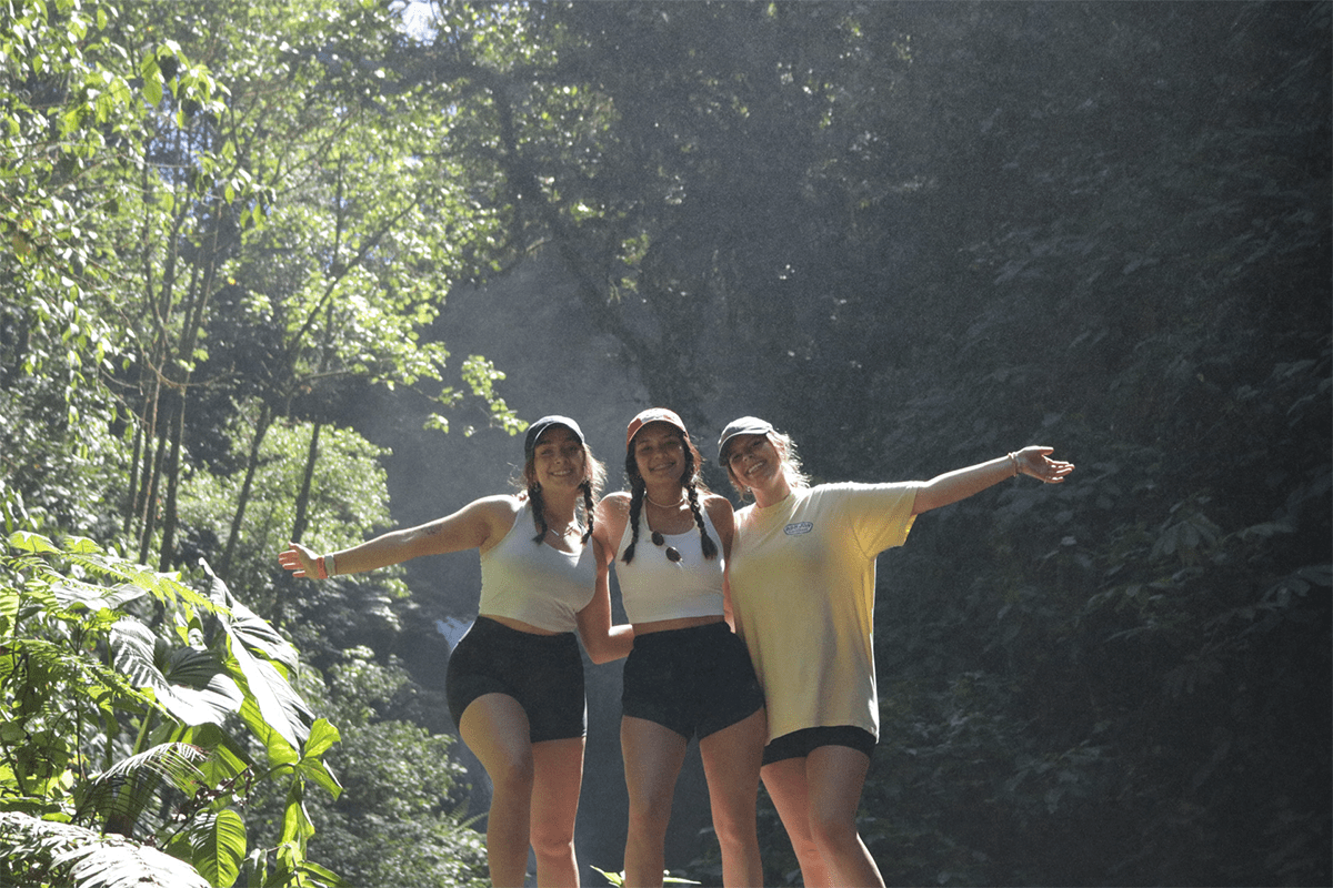 Three girls standing on a rock in front of a waterfall in Costa Rica